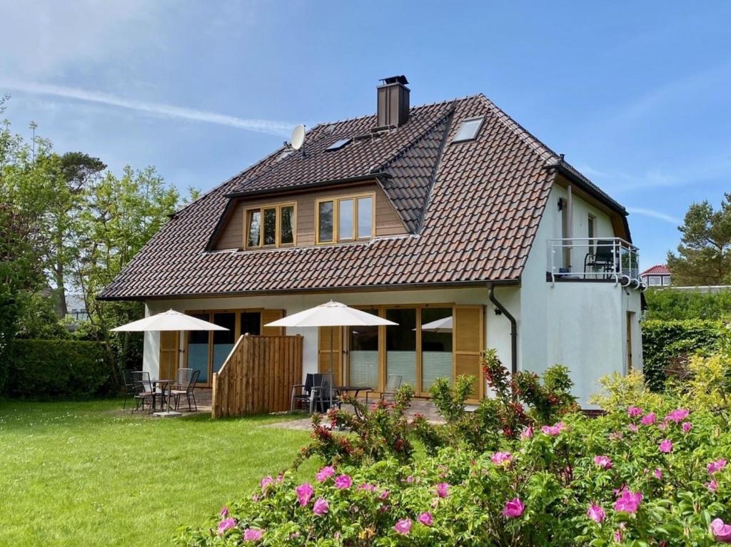 a house with chairs and umbrellas in the yard at Haus Sonnenwinkel, FW 3 in Zingst