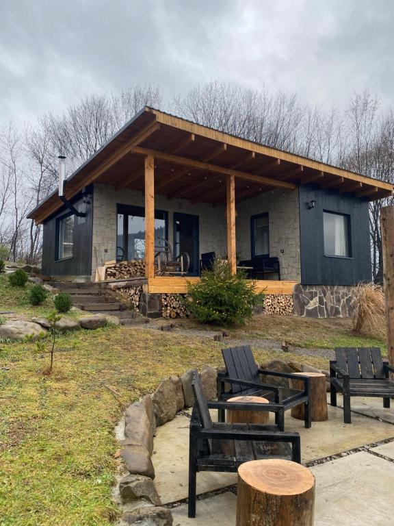 une maison avec des chaises et des tables devant elle dans l'établissement Гірські будиночки, à Zhdenievo