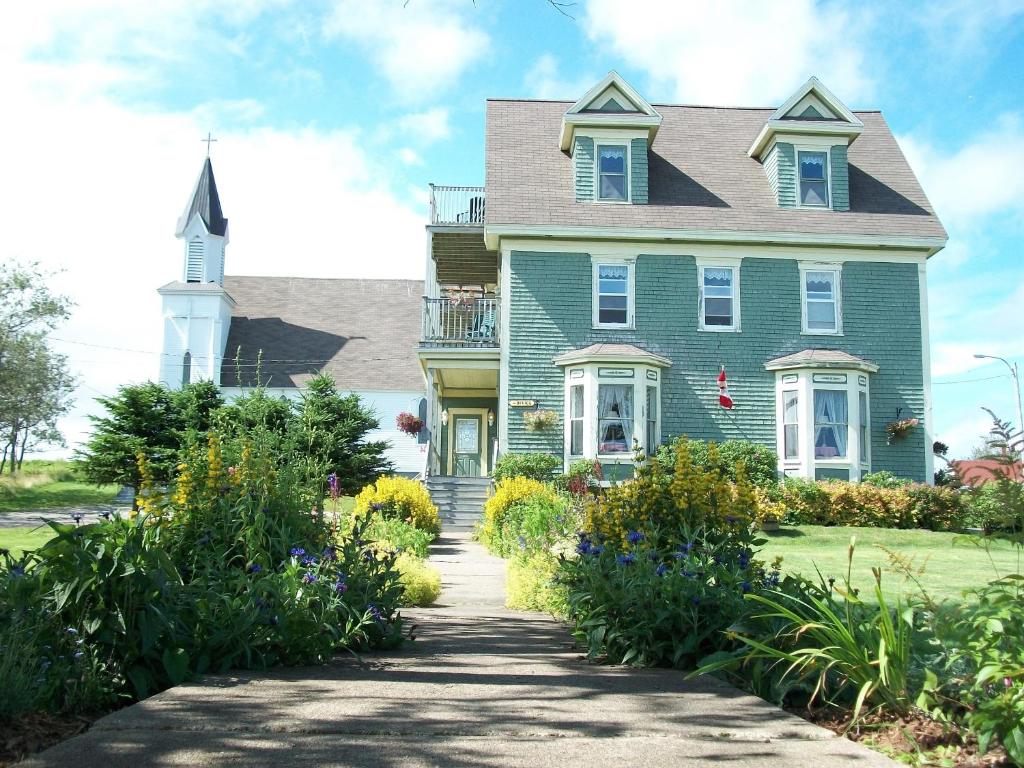 ein grünes Haus mit einem Kirchturm und einer Kirche in der Unterkunft Louisbourg Heritage House in Louisbourg