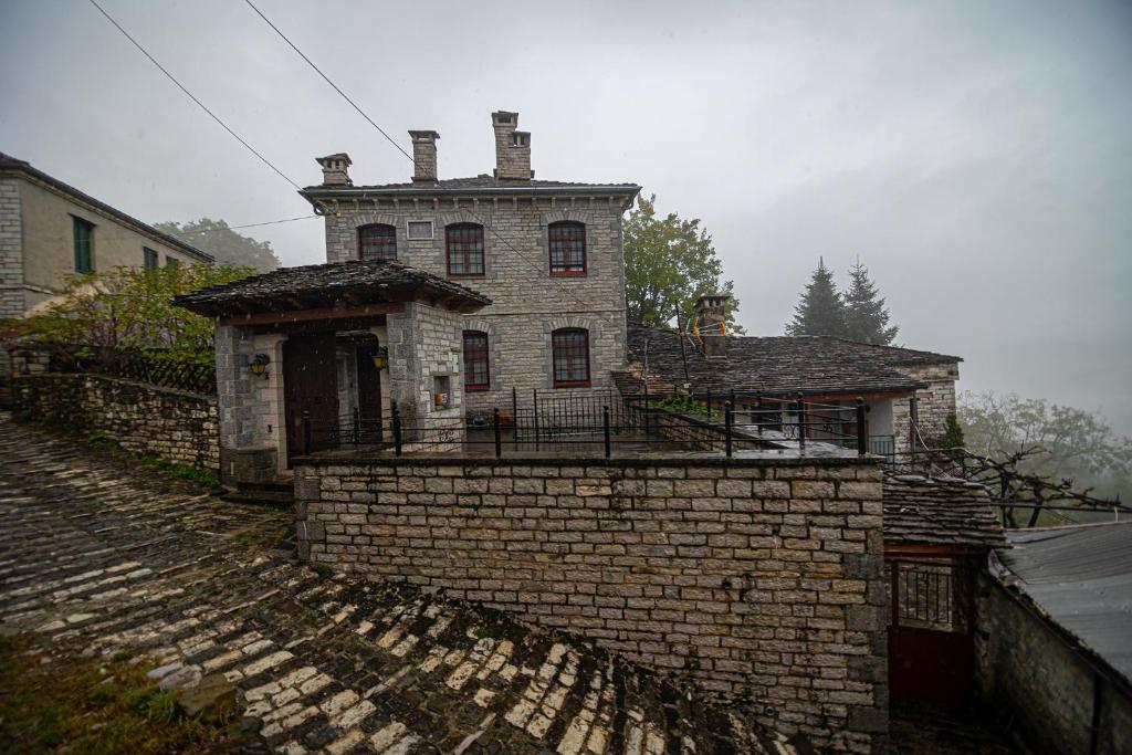 una vieja casa de ladrillo sentada en la parte superior de una pared de ladrillo en Villa Georgia, en Vitsa