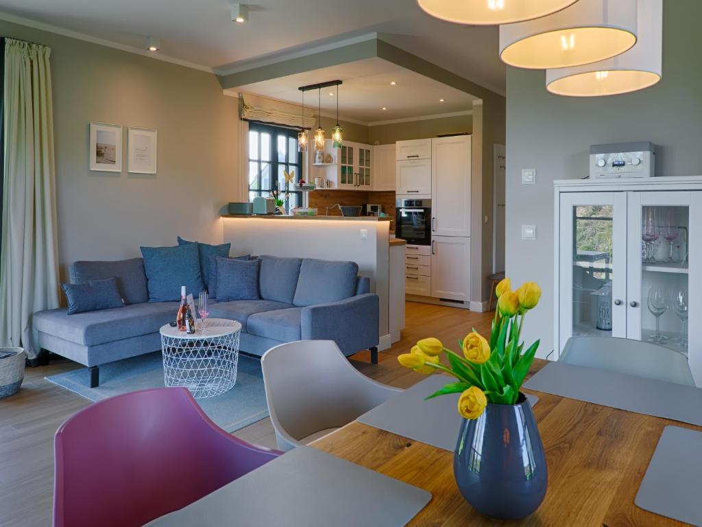ein Wohnzimmer mit einem blauen Sofa und einem Tisch in der Unterkunft Reetland am Meer - Premium Reetdachvilla mit 3 Schlafzimmern, Sauna und Kamin F27 in Dranske