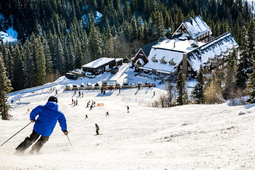 a person skiing down a snow covered slope in front of a lodge at Hotell Fjällgården Ski-In Ski-Out in Åre