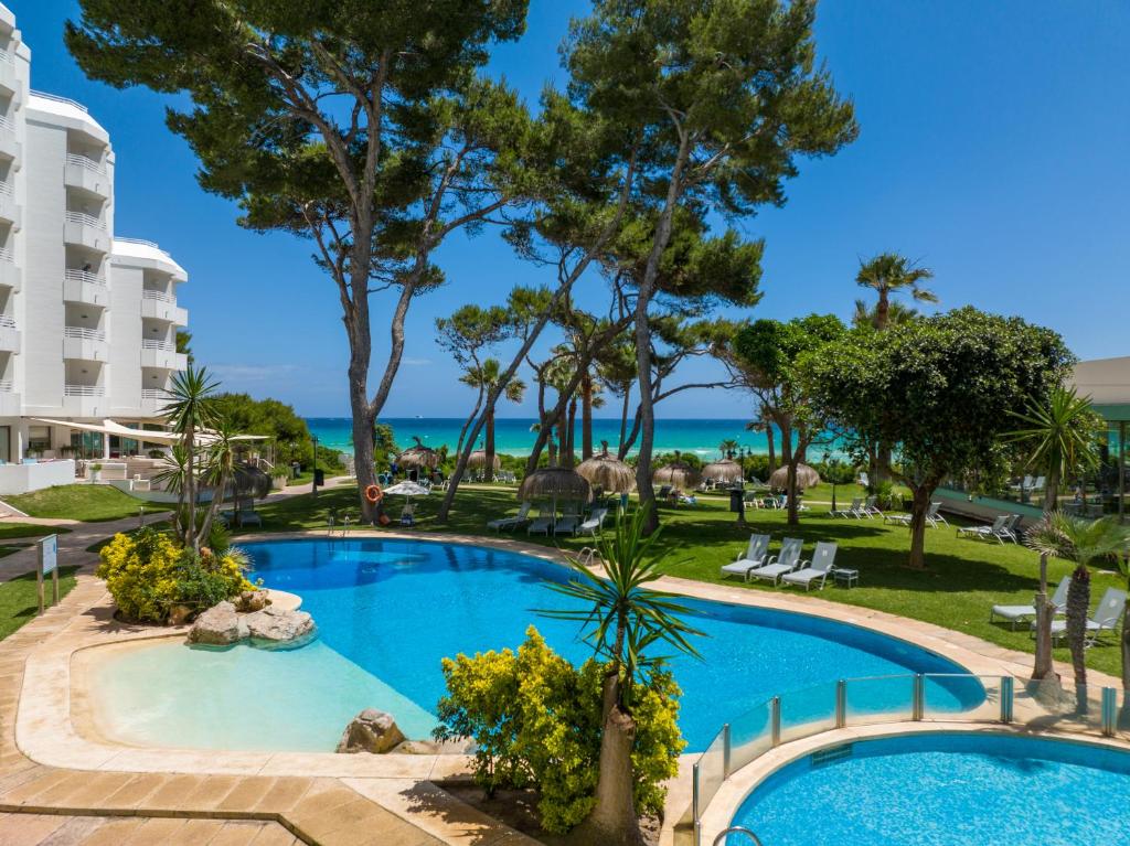a pool at the resort with the ocean in the background at Playa Esperanza Resort Affiliated by Meliá in Playa de Muro