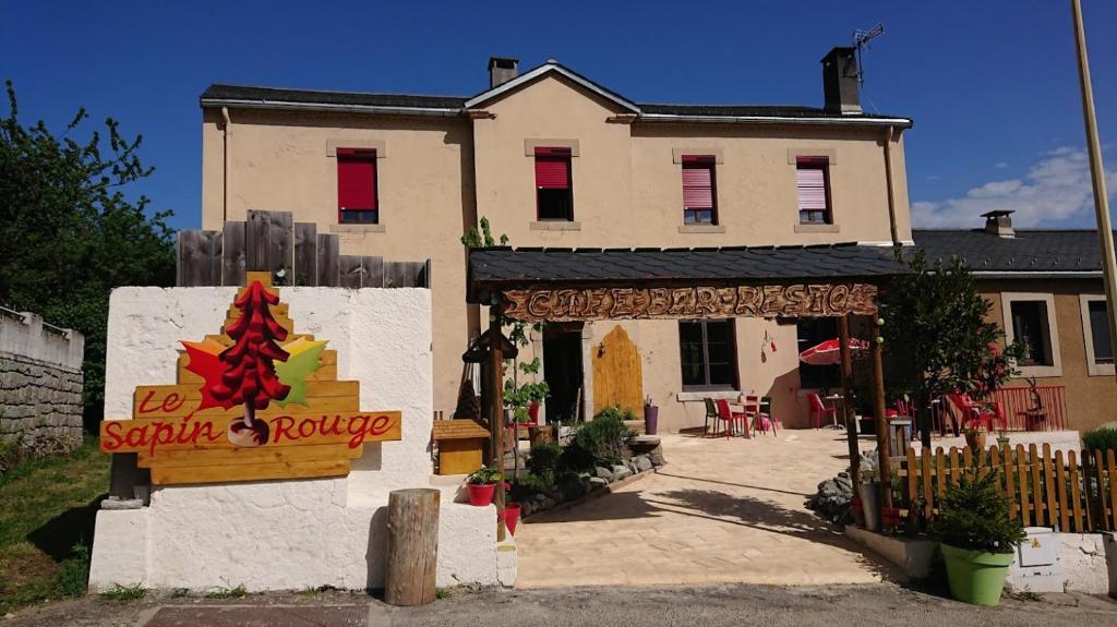 une grande maison avec un panneau en face de celle-ci dans l'établissement Le sapin rouge, chambres d'hôtes - restaurant - bar, à Artigues