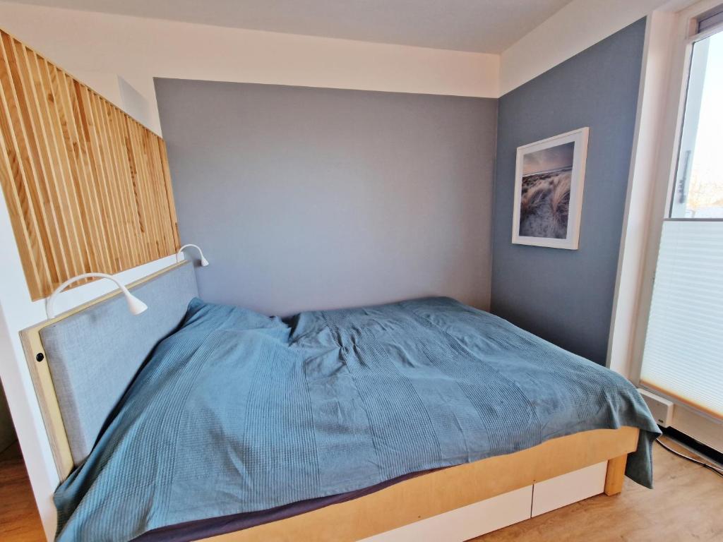 um quarto com uma cama com um cobertor azul em Stadtgebiet EIC-018 em Heiligenhafen