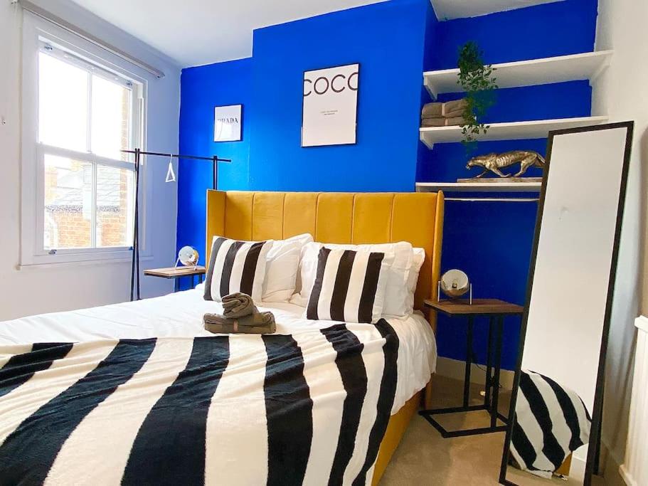a blue bedroom with a bed with a yellow headboard at Beautiful City Centre Home With Garden and Parking in Oxford