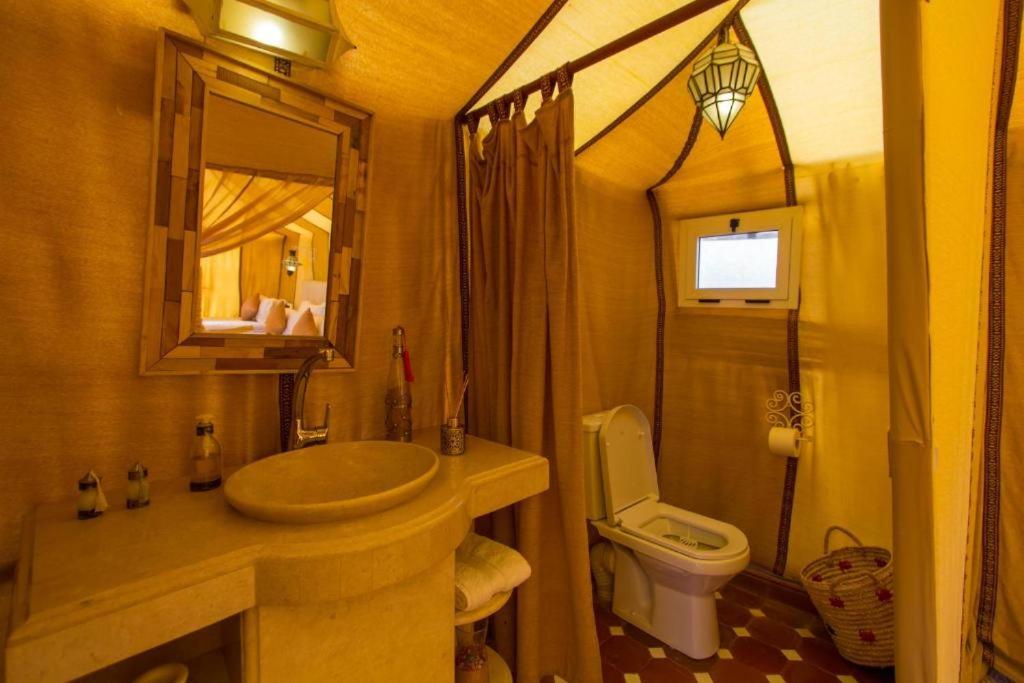a bathroom with a sink and a toilet and a mirror at Mourad desert camp in Merzouga