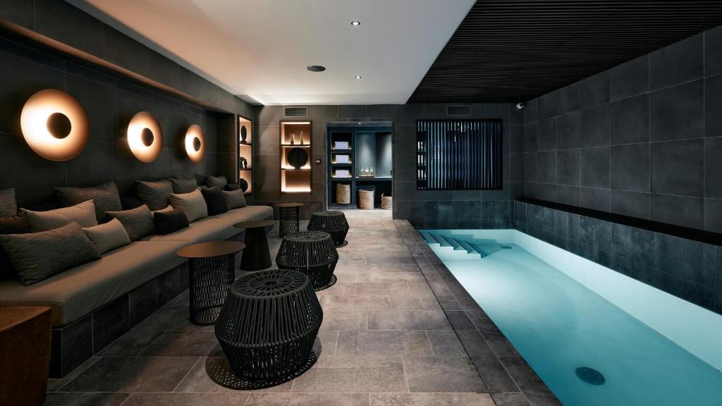 a hotel lobby with a pool and a couch and tables at Le Bellune Paris in Paris