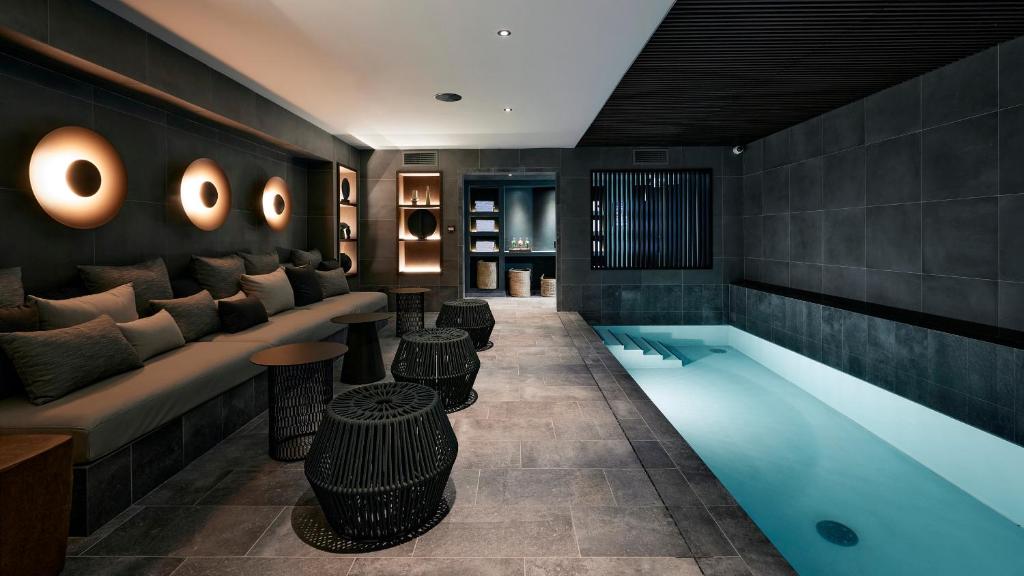 um átrio de hotel com uma piscina, um sofá e mesas em Le Bellune Paris em Paris