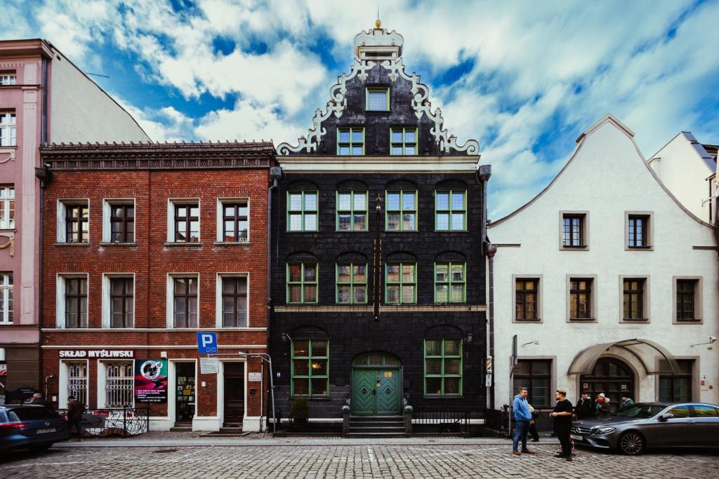 un edificio alto y negro con una torre de reloj en una calle en Heban Hotel en Toruń