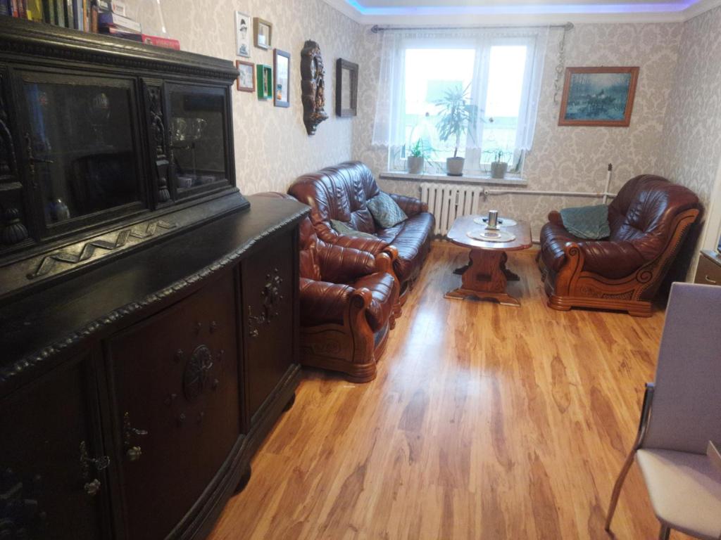 a living room with leather chairs and a flat screen tv at Apartament Mazurski in Szczytno