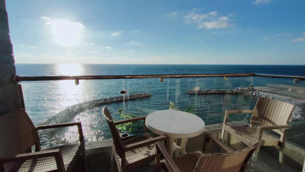 a balcony with a table and chairs and the ocean at Asafra Hotel Apartments in Alexandria