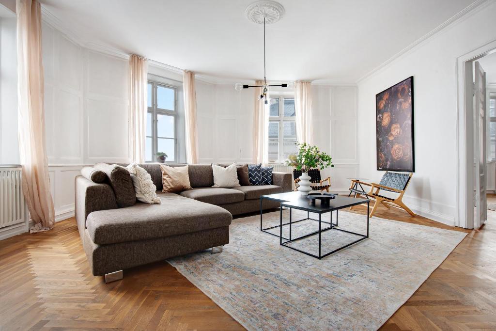 Sanders Square - Spacious Six-Bedroom Apartment Near Amalienborg في كوبنهاغن: غرفة معيشة مع أريكة وطاولة