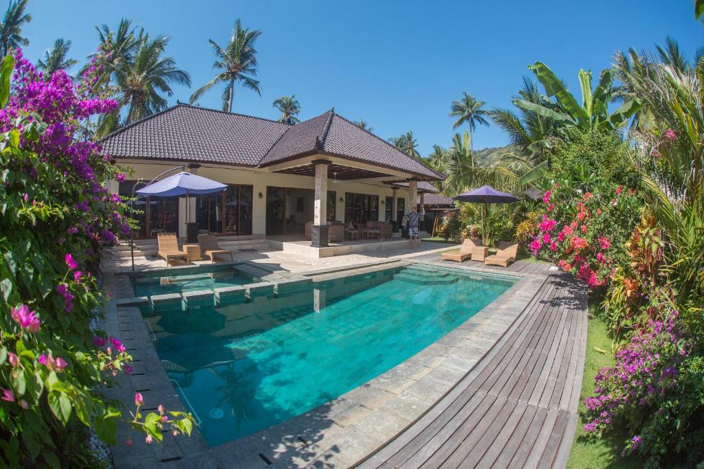 a villa with a swimming pool and palm trees at Villa Barong in Candidasa