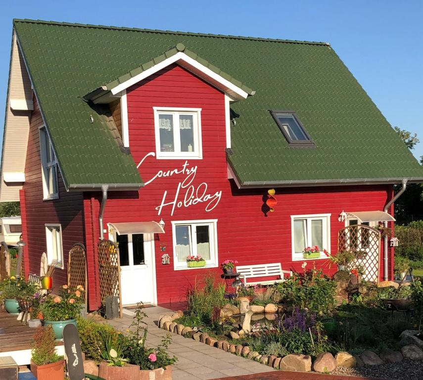 ein rotes Haus mit grünem Dach in der Unterkunft Country Heaven in Grömitz