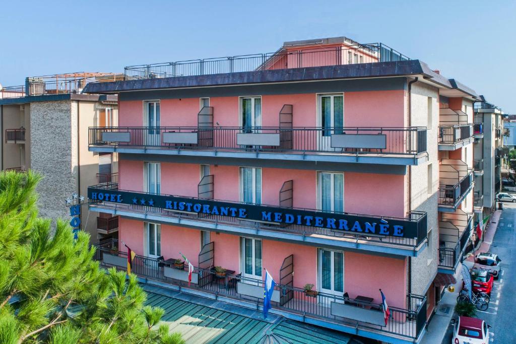 un edificio rosa alto con un cartel. en Hotel Mediterranée, en Spotorno