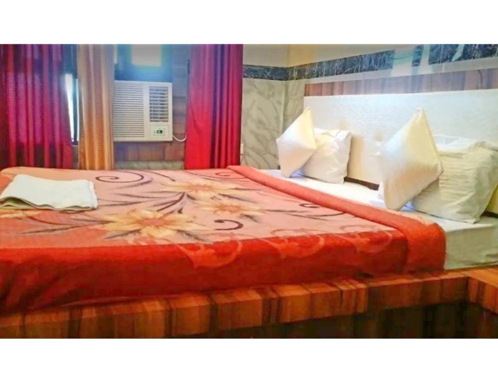 1 cama con manta roja y almohadas blancas en Hotel Kuber, Bhabua, en Bhabua