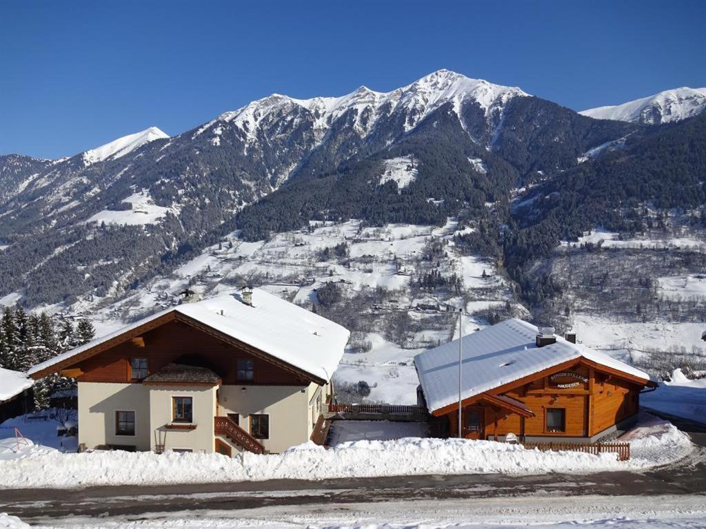 a house covered in snow with mountains in the background at Hausebengut in Bad Gastein