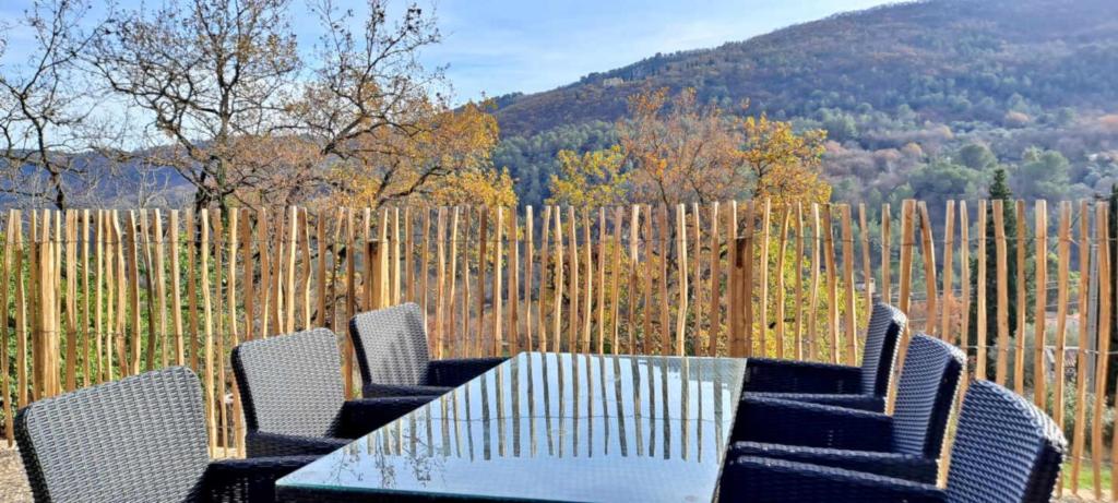 una mesa, sillas y una valla de madera en Quiet and Nature Holiday Home on the Cote dAzur, en Le Bar-sur-Loup