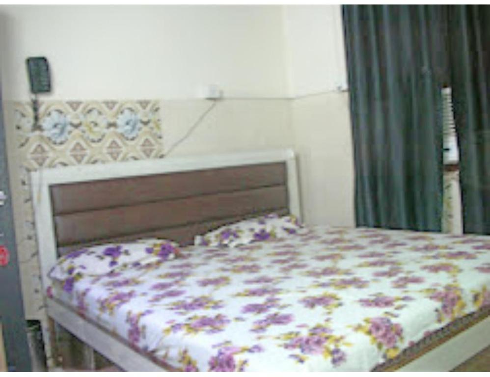 a bedroom with a bed with a floral comforter at Hotel Kanha Dham, Kanpur in Kānpur