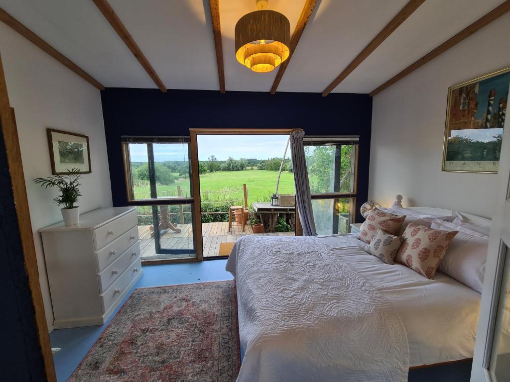 a bedroom with a bed and a large window at Countryside Garden Summer House in Calne