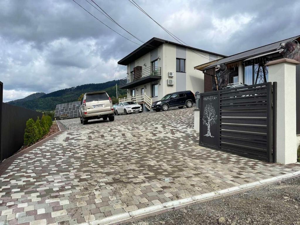a house with cars parked in front of a driveway at Садиба Кичера Gold in Mizhhirʼʼya