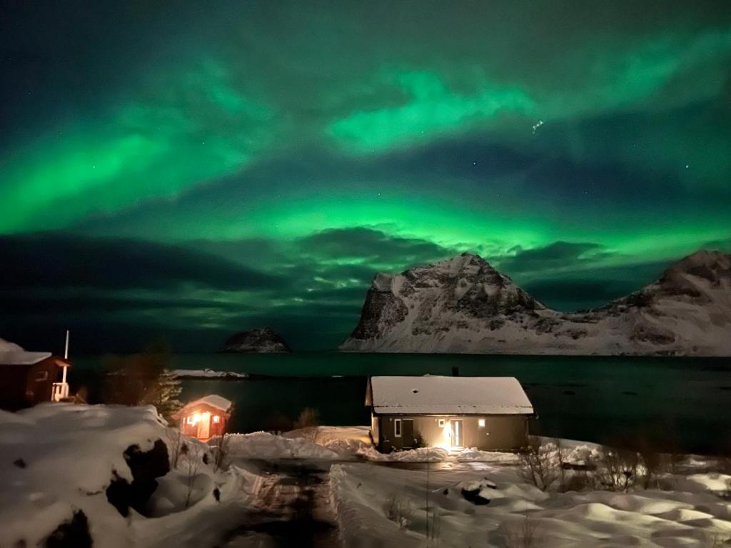 an aurora shines in the sky over a house at Magic views and walking distance to best beaches in Leknes