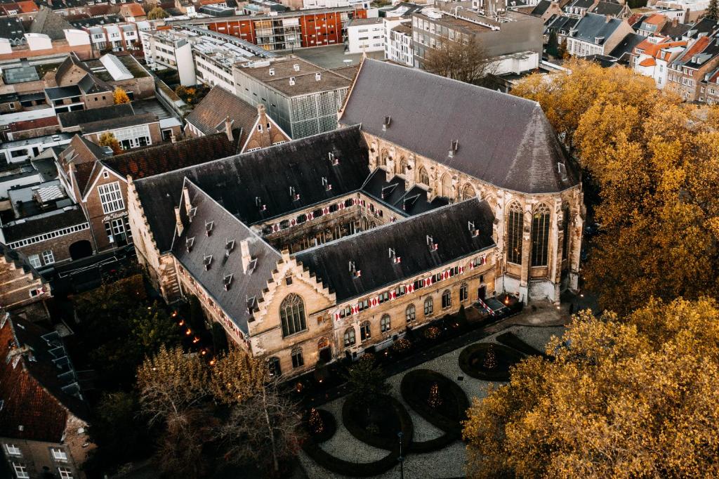an old building with a black roof in a city at Kruisherenhotel Maastricht - Oostwegel Collection, member of Design Hotels in Maastricht