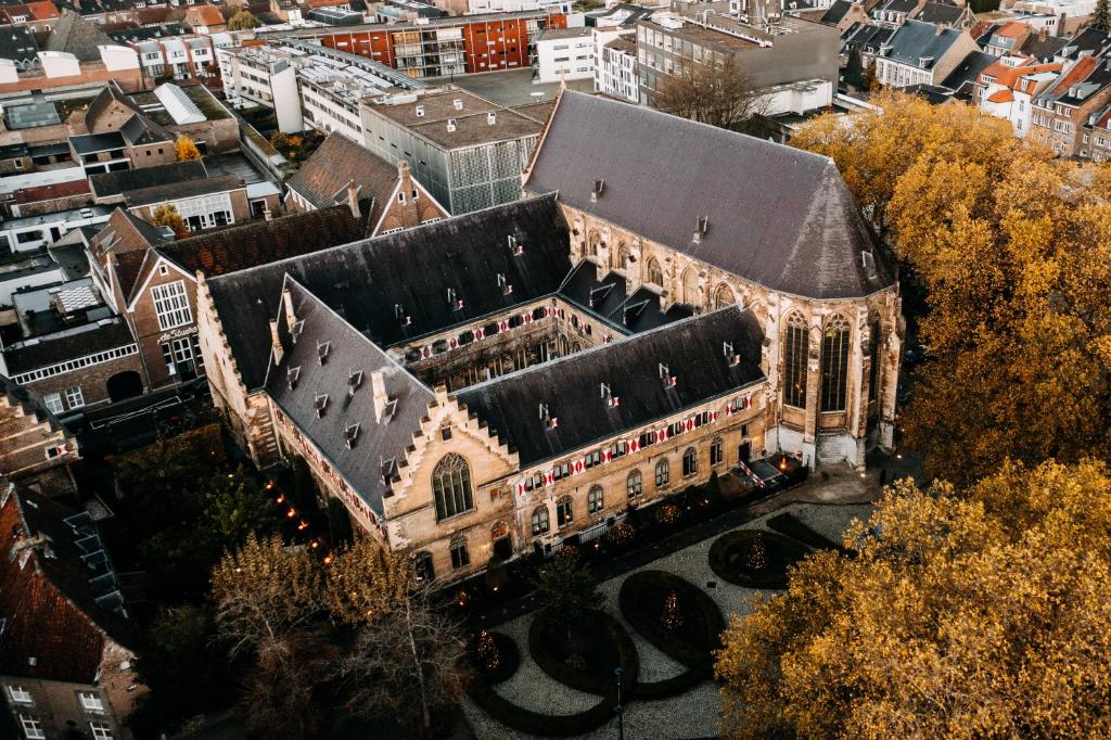 ein altes Gebäude mit schwarzem Dach in einer Stadt in der Unterkunft Kruisherenhotel Maastricht - Oostwegel Collection, member of Design Hotels in Maastricht