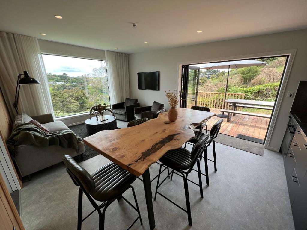 a kitchen and living room with a wooden table and chairs at Hidden Valley Waiheke in Palm Beach