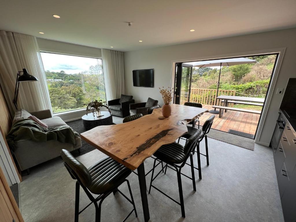 una cucina e un soggiorno con tavolo e sedie in legno di Hidden Valley Waiheke a Palm Beach