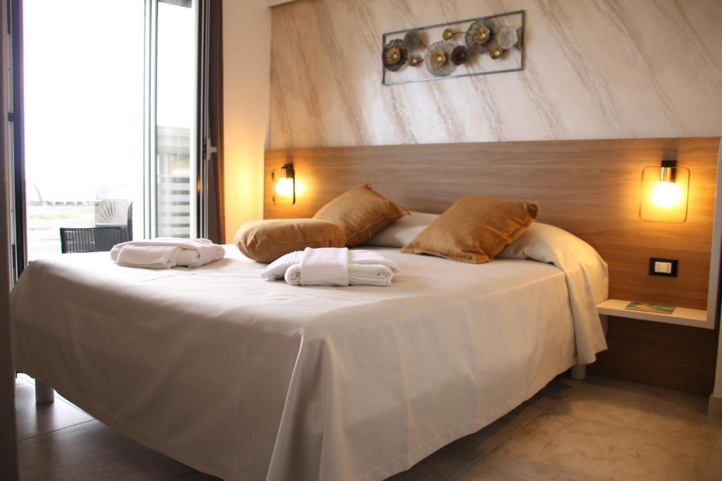 1 dormitorio con 1 cama blanca grande y 2 toallas en B&B Glass Paradise en Catanzaro