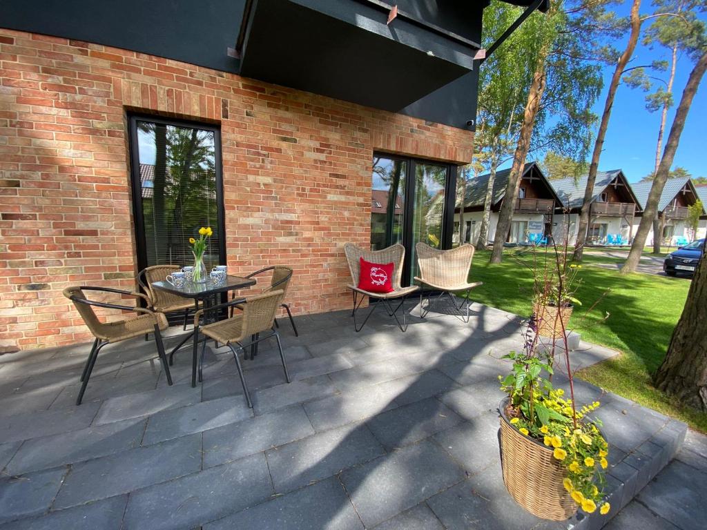 a patio with a table and chairs and a brick wall at Apartament Poezja Ciszy in Dębki