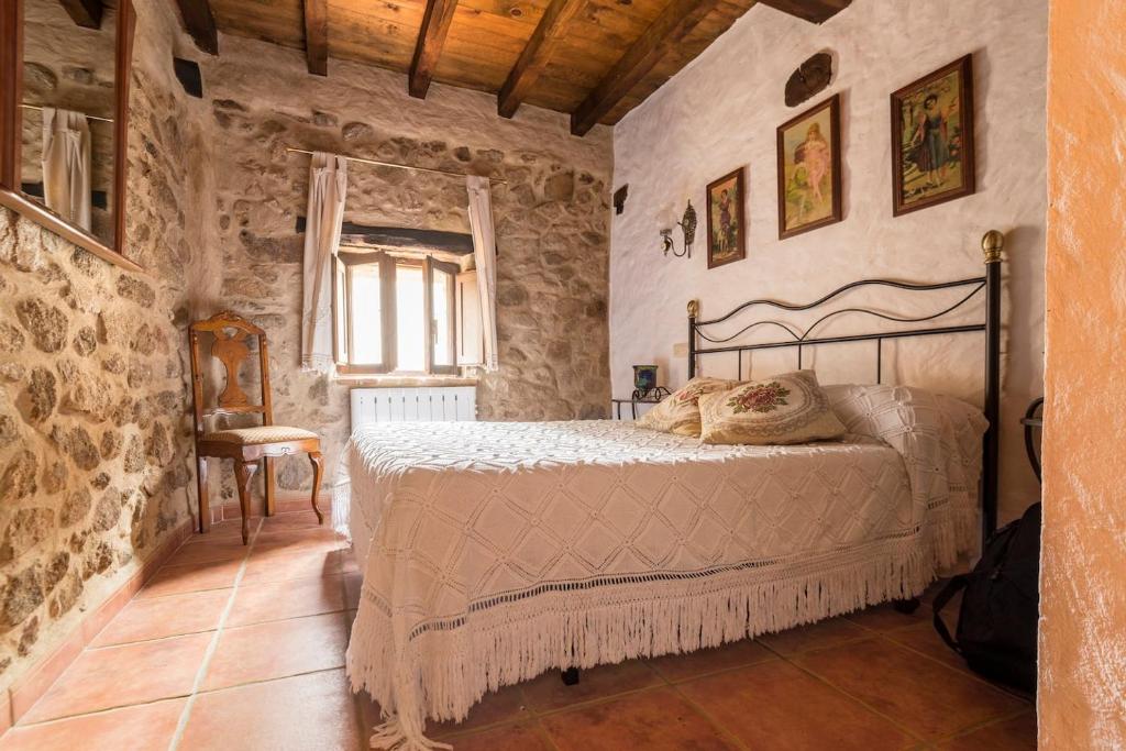 ein Schlafzimmer mit einem Bett in einem Steinzimmer in der Unterkunft CASA PETRA in Miranda del Castañar