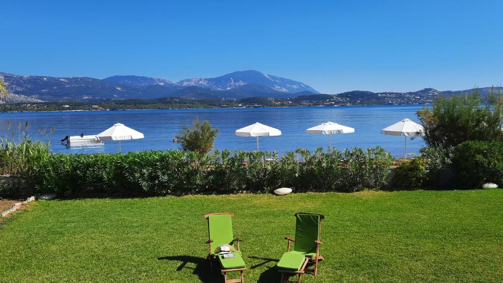 two chairs and umbrellas on a lawn next to a lake at Alekos Beach Houses-Alekos Beach Complex in Lixouri