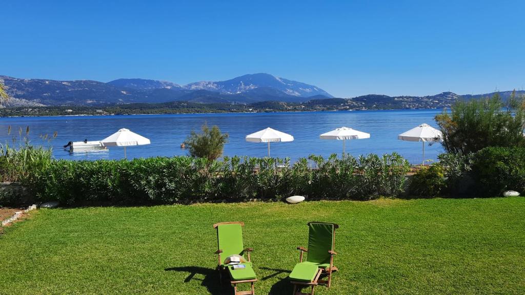 twee stoelen en parasols op een gazon naast een meer bij Alekos Beach Houses-Alekos Beach Complex in Lixouri