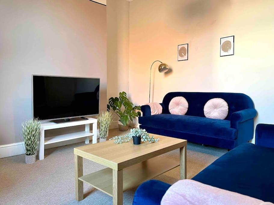 a living room with a blue couch and a tv at Close to city centre-Quayside bright apartment in Gateshead