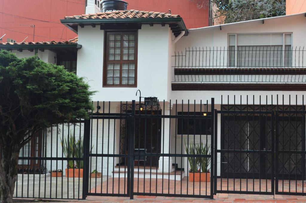 a house with a fence and a building behind it at Casa Prada Bed & Breakfast in Bogotá