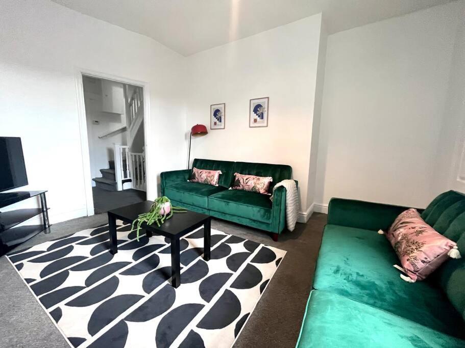 un soggiorno con 2 divani verdi e un tappeto di 5 BDRM house less than 10 mins to Newcastle a Gateshead
