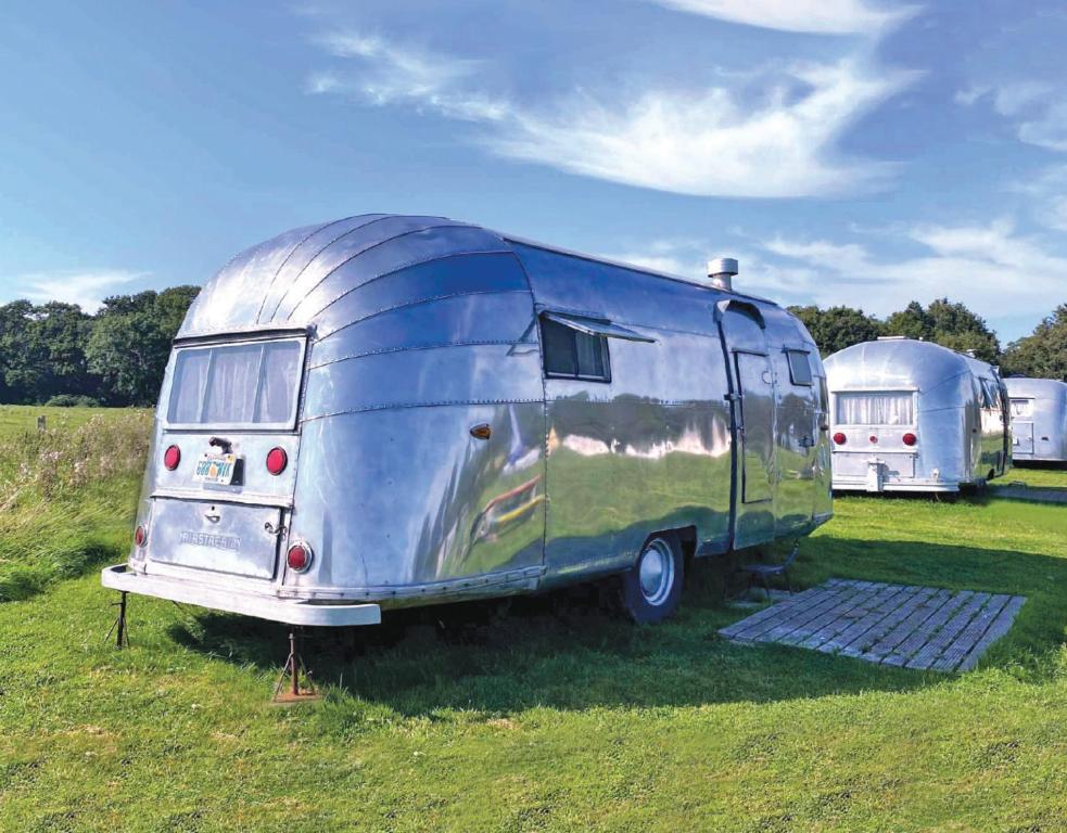 een oude blauwe trailer geparkeerd in een veld bij Retro Staycations in Ryde