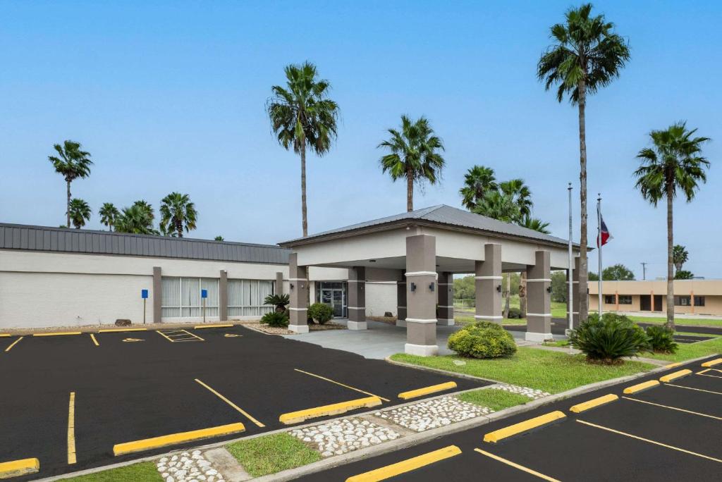 a parking lot in front of a building with palm trees at Quality Inn in Alice