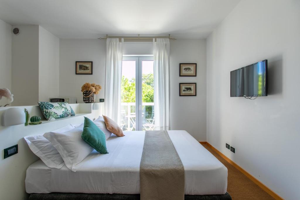 a white bedroom with a large bed and a tv at Harvey Suites Hotel & Residence in Lido di Jesolo