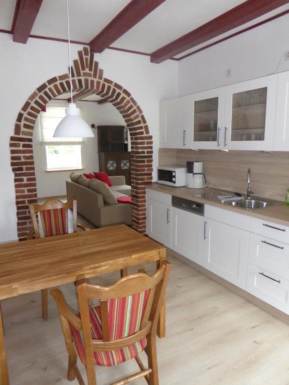 a kitchen and living room with a wooden table and a dining room at Ferienwohnung Elise im Gulfhof am Kanal in Großefehn 