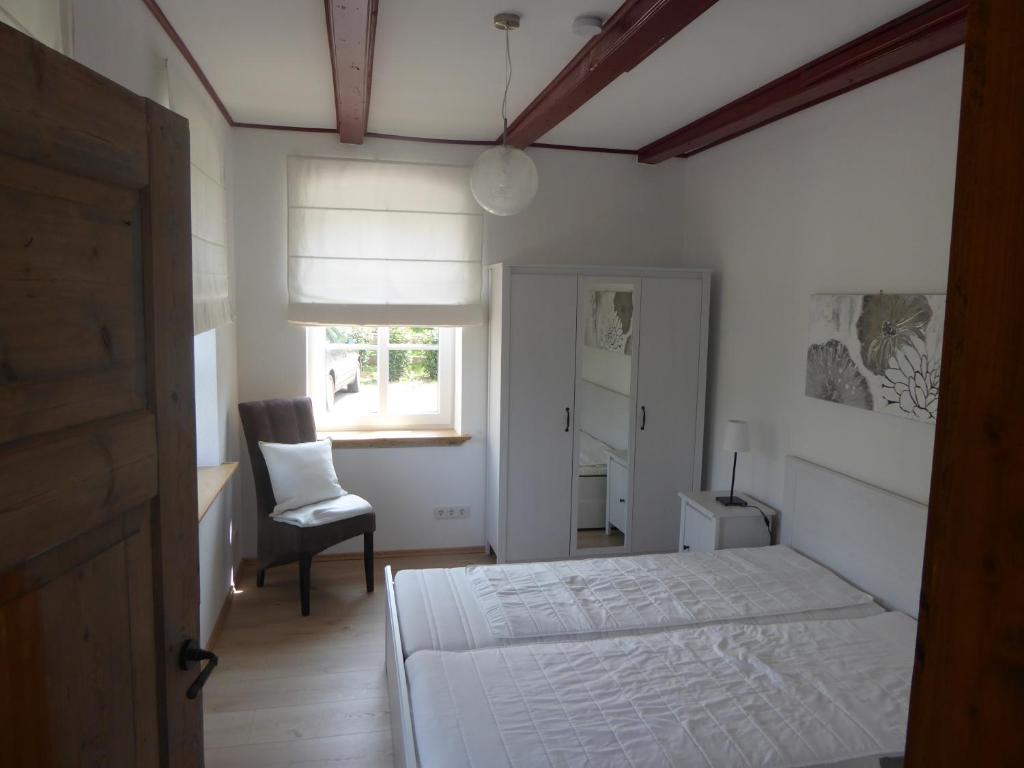 a bedroom with a bed and a chair and a window at Ferienwohnung Elise im Gulfhof am Kanal in Großefehn 