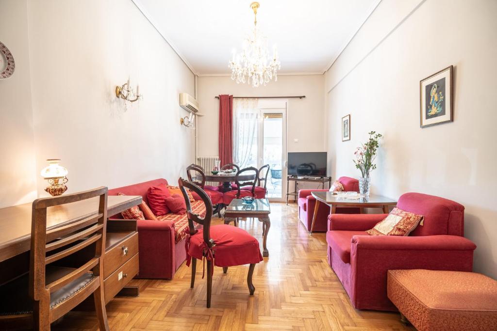 een woonkamer met rode meubels en een kroonluchter bij Family apartment at Kalithea 2 bedrooms 4 pers in Athene