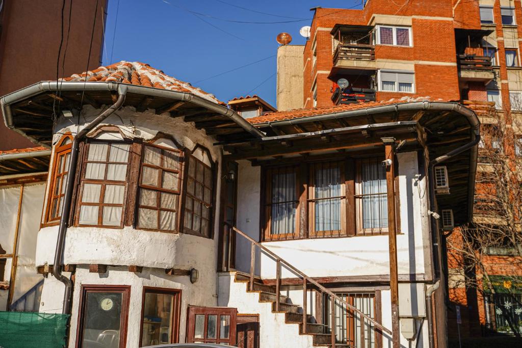 an old house with a staircase in front of a building at Old House Apartment in Pristina