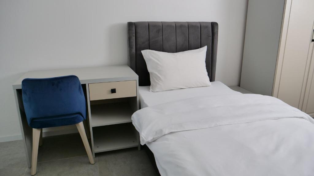 a bedroom with a bed and a desk and a blue chair at Evsenn Hotel in Reutlingen