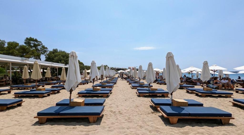 a row of lounge chairs and umbrellas on a beach at Parthenis Riviera Hotel in Athens