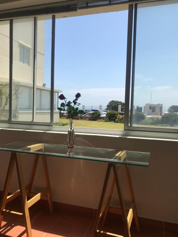 einem Glastisch vor einem Fenster mit einer Vase mit Blumen in der Unterkunft Mouille Point Villa Capri in Kapstadt