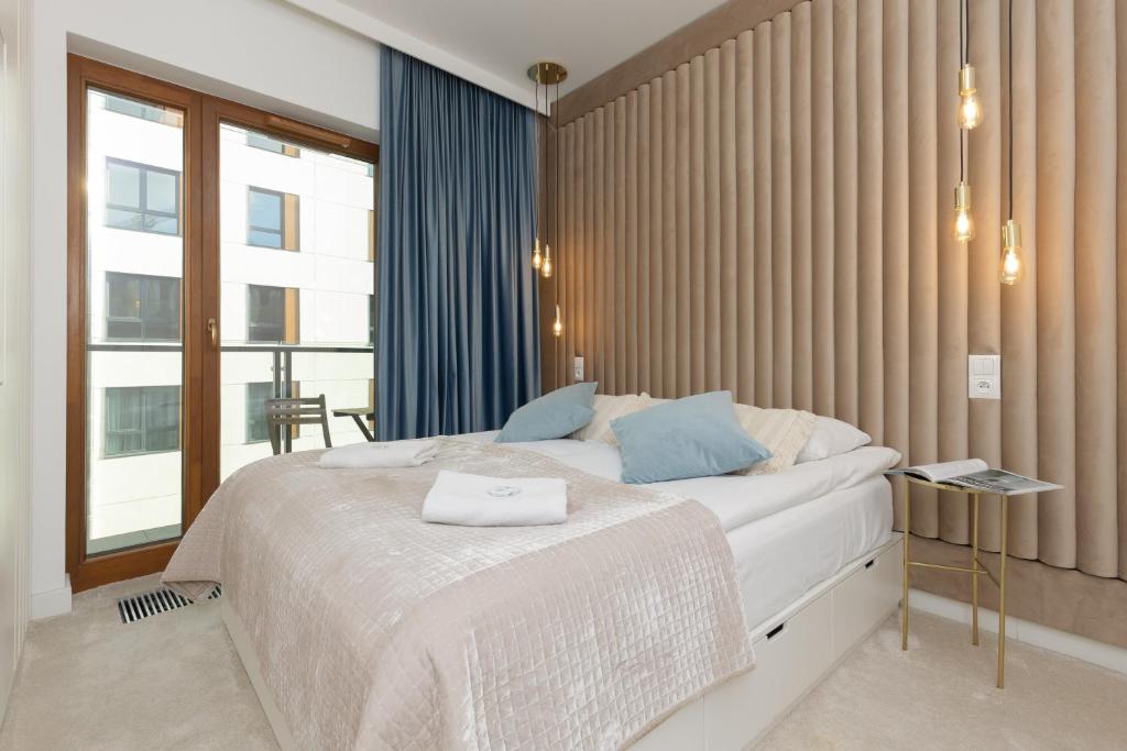 una camera da letto con un grande letto bianco con cuscini blu di Apartments Warsaw Pawia by Renters a Varsavia